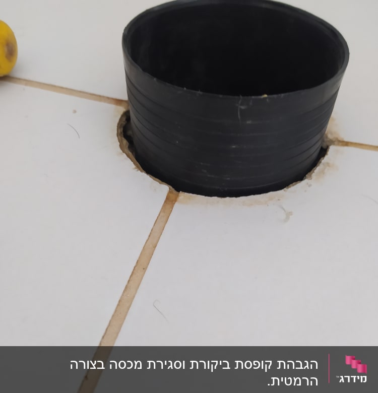 צינור שחור עגול בתוך חור ברצפה לבנה